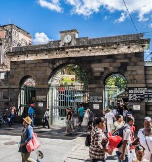 a crowd of people walking in front of a building with a clock