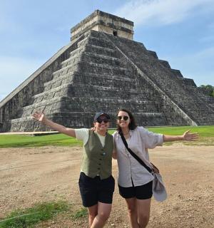 two women standing in front of a pyramid