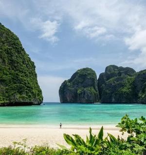 a person standing on a beach in the ocean with cliffs