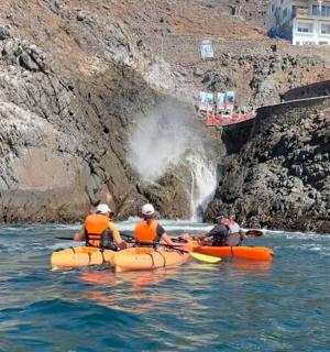 three people in kayaks in the water near a waterfall