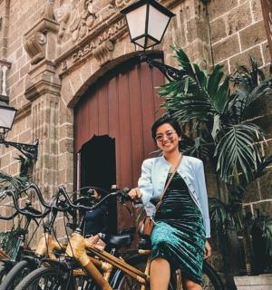 ผู้หญิงคนหนึ่งกำลังนั่งอยู่บนจักรยานหน้าอาคาร