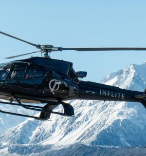 a helicopter flying over a snow covered mountain