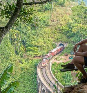 a man sitting on a ledge looking at a train