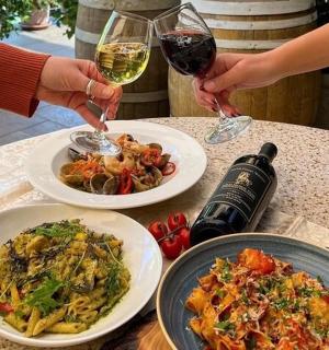 dva lidé držící sklenice vína na stole s jídlem