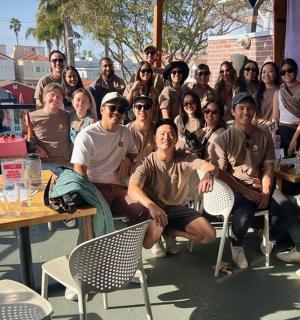 skupina lidí pózujících pro fotografii u stolů