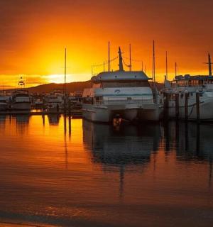 група чамаца усидрених у луци у залазак сунца