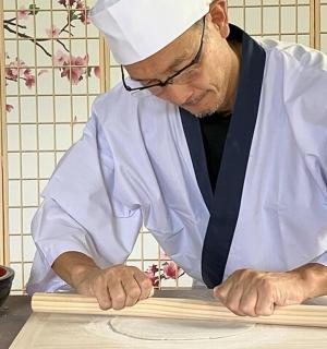 一名身穿厨师服的男子正在切割一块木头