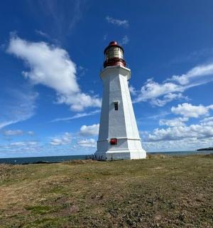 a white lighthouse sitting on top of a grass field