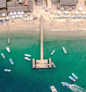 an aerial view of boats in the water near a beach