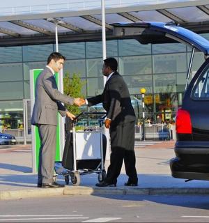 two men shaking hands in front of a car