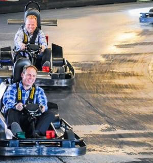 dva muži jedoucí v autíčkách na horské dráze