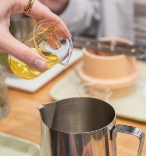a person pouring a glass of oil into a mug