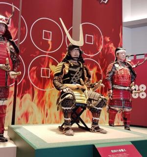 three people dressed in ancient armor on a stage