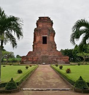 a monument in a field with two palm trees