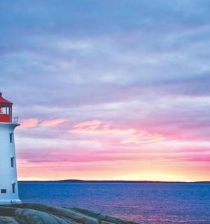 a lighthouse on the shore of the ocean at sunset