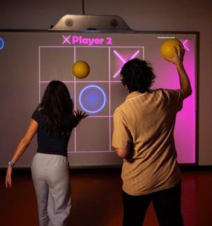 คนสองคนกำลังเล่นวิดีโอเกมอยู่ในห้อง