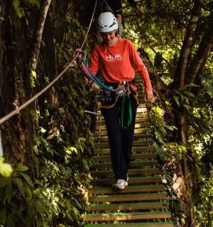 a woman walking on a rope bridge in the forest
