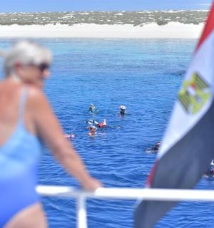 a woman in a blue bikini standing on a boat in the water