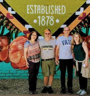 skupina lidí stojících před nástěnnou malbou