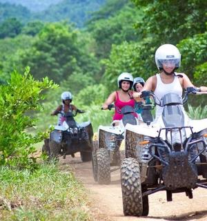 一群人骑着四轮摩托车在土路上行驶