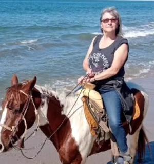 a woman riding a horse on the beach