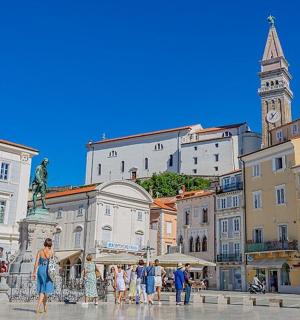 skupina lidí procházejících se po městě s hodinovou věží