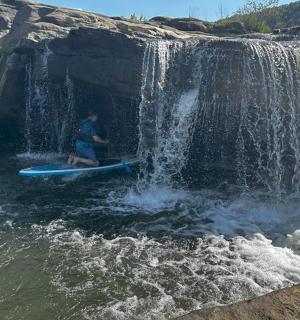 a man on a surfboard in front of a waterfall