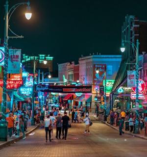 a crowd of people walking down a busy city street at night