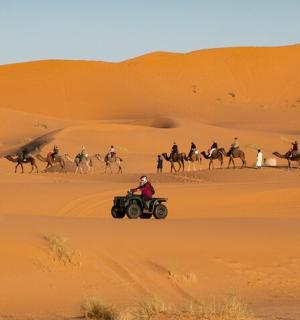 skupina lidí jedoucích na čtyřkolkách v poušti