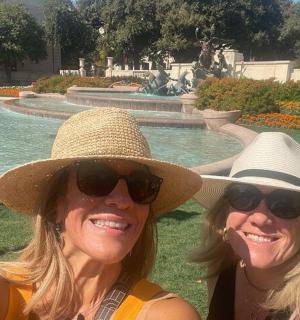 dvě ženy v kloboucích sedící před fontánou