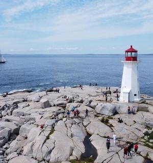 sebuah rumah api di pantai berbatu dengan bot di dalam air