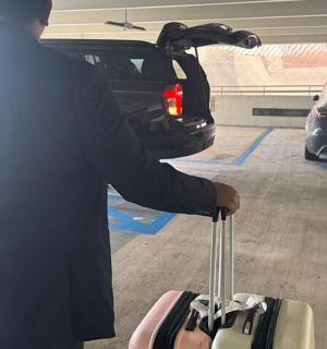 a man standing in a parking lot with a suitcase
