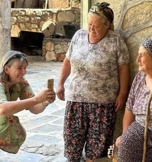 three older women sitting next to each other holding a cell phone