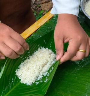 a person cutting rice on a banana leaf