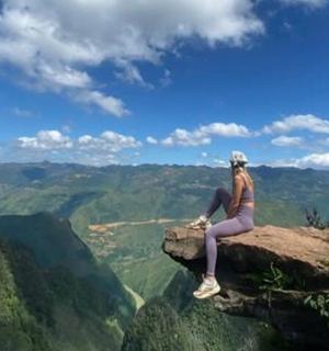 一位妇女坐在山边的一块岩石上