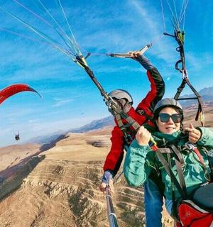 dva lidé sestupují na padáku nad kaňonem