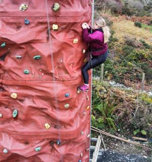 a woman is climbing a rock climbing wall
