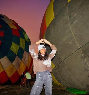 seorang wanita berdiri di hadapan dua belon udara panas