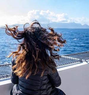 一位女士坐在船上眺望大海