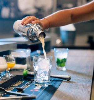 一个人把饮料倒进桌上的玻璃杯里