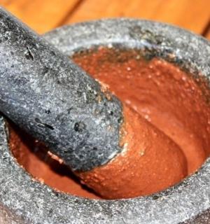 hmoždíř a tlouček trčící z červené mísy