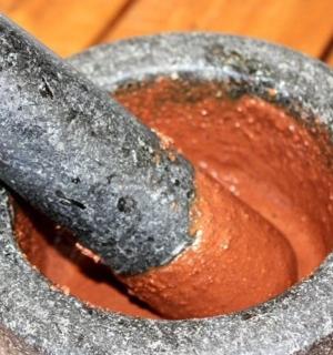 hmoždíř a tlouček trčící z červené mísy