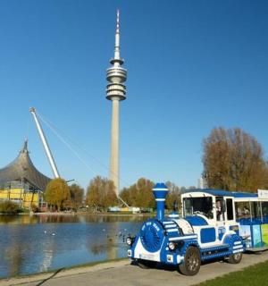 a small bus parked next to a lake with a tower