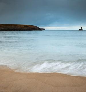 a beach with the ocean and rocks in the water