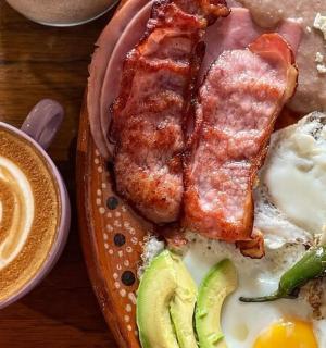 ein Teller Frühstücksspeise mit Eiern, Speck und einer Tasse Kaffee
