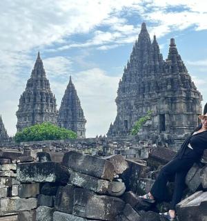 a woman sitting on a stone wall in front of a temple