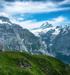 a house on a green hill with mountains in the background