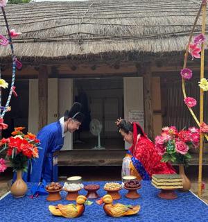 two people standing in front of a building with flowers