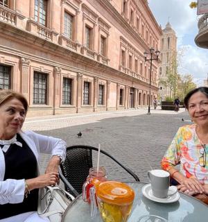 two women sitting at a table in front of a street