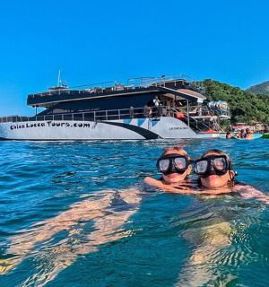two people in the water in front of a boat